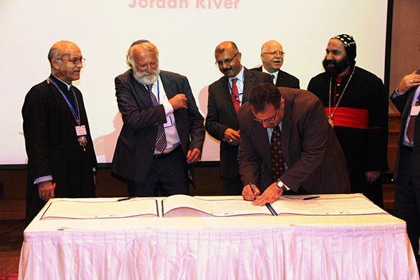 A professor of Islamic studies signs the Covenant after Rabbi Awraham. Two Syrian Orthodox bishops and the directors of FoEME look on in the background
Photo: Ted Swagerty