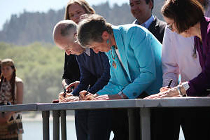 Figure 11. On April 6, 2016 California Gov. Jerry Brown, U.S. Secretary of the Interior Sally Jewell, and Oregon Gov. Kate Brown sign the new Klamath Hydroelectric Settlement Agreement as Yurok women look on.
