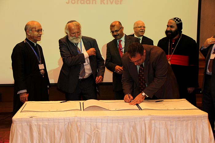 A professor of Islamic studies signs the Covenant after Rabbi Awraham. Two Syrian Orthodox Bishops and the Directors of FoEME look on in the background.